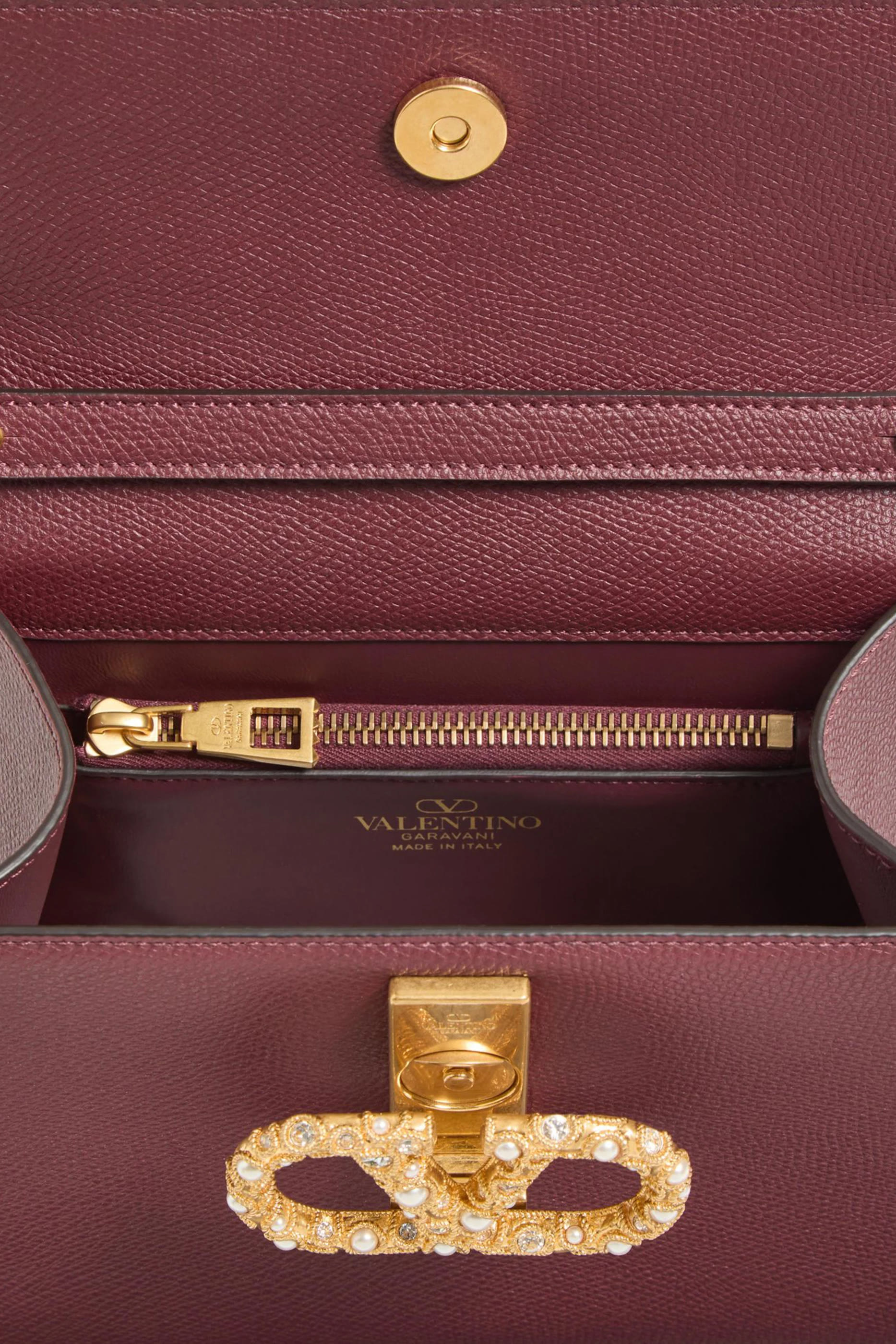 حقيبة يد صغيرة بحلية شعار الماركة المرصعة بأحجار